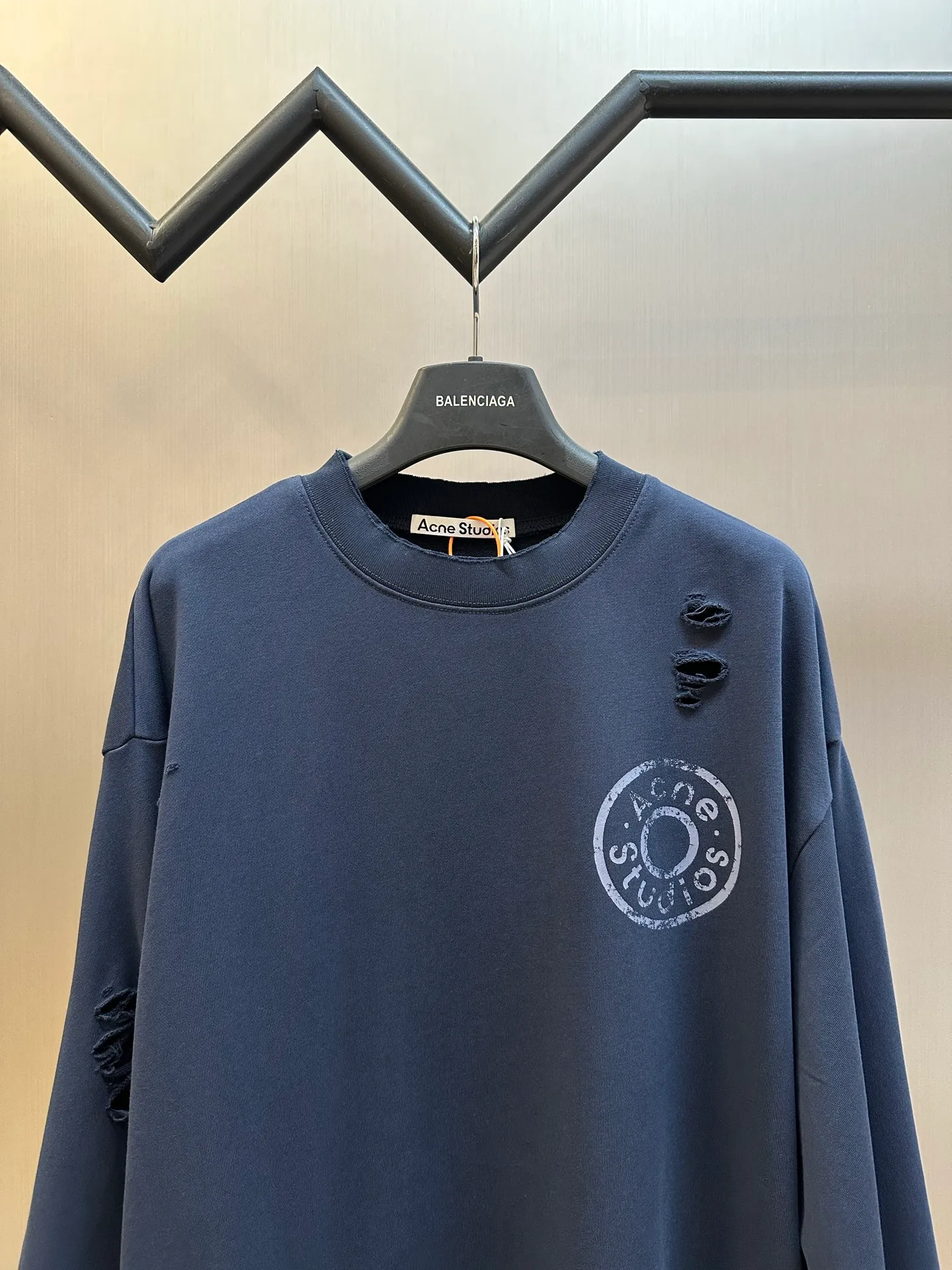 Ac Studios distressed logo sweatshirt Customized etched soft-extract raw cotton fleece, deep dark blue is quiet and restrained, matte fog base color, symbiotic with the destructive texture, Retro pioneer style, denim rivet style logo printing on the chest, replica of the old steel seal embossed texture, the color will naturally fade with the washing of the garment, and the whole body will be more Artificially torn holes are carefully arranged, and the raw edges of the rips are stretched out wantonly, replicating the wear and tear traces eroded by time, destroying and deconstructing the regular shackles of standard clothing, integrating decadent street aesthetics and Nordic minimalist design genes, creating a pioneering ready-to-wear product with outstanding character. Glue printing is used. The chest printing is modified by the film screen three times. The glue liquid paint is used to print the pattern on the fabric, and the fabric is baked to fix the printed pattern. Many parts of the body of the garment are worn and worn at regular intervals, with manual brush marks added to add texture and depth to the surface of the garment to imitate the texture of natural wear and tear size: s m l xl